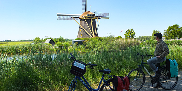 .Radreise Südholland Radfahrer vor Windmühle .
